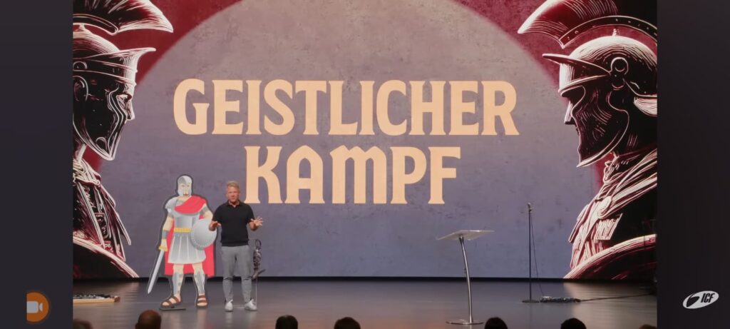 Screenshot auf Live-Übertragung einer Predigt aus der ICF Zürich mit Leo Bigger vom 26.10.2025. Bühne, im Hintergrund zwei Krieger in Kampfausrüstung und Schrift "Geistlicher Kampf": https://www.youtube.com/watch?v=VA56tlvw0GA